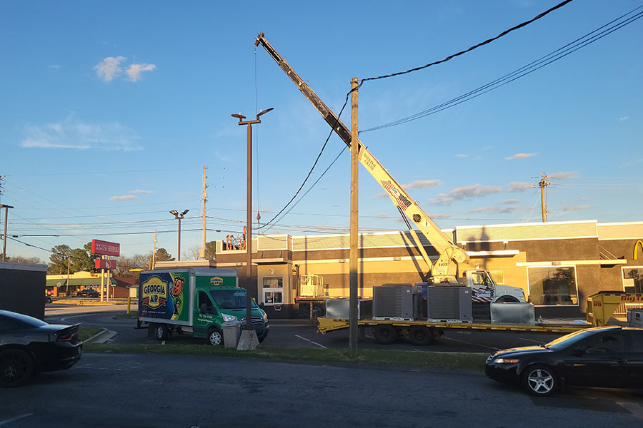 Crane lifting HVAC units onto a commercial building roof