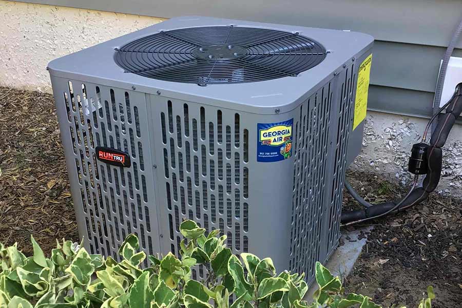 Outdoor HVAC unit installed near a house with greenery
