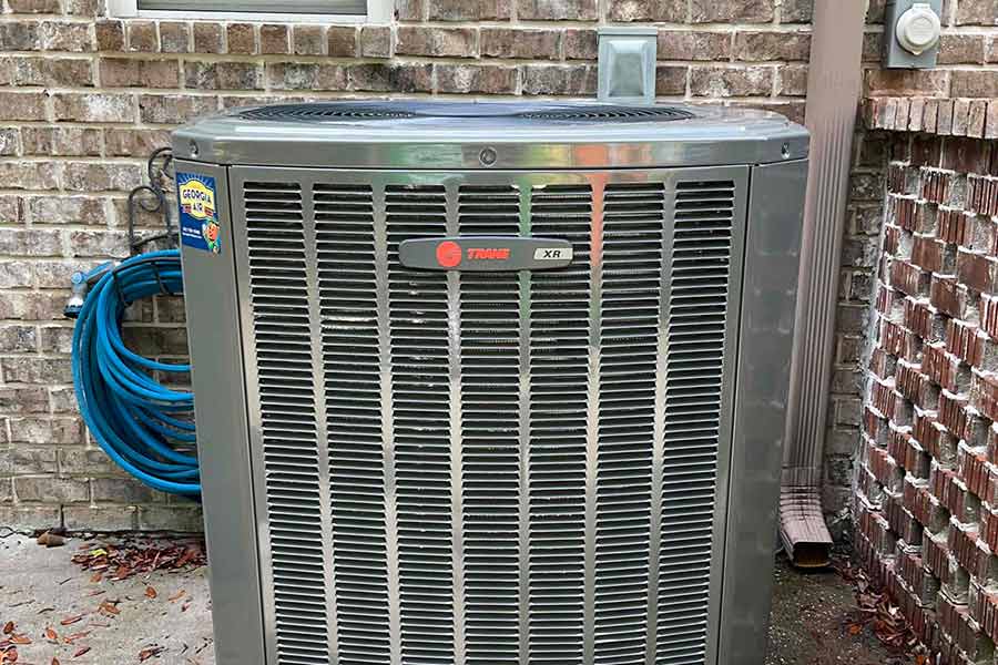 HVAC condenser unit installed outside a brick house