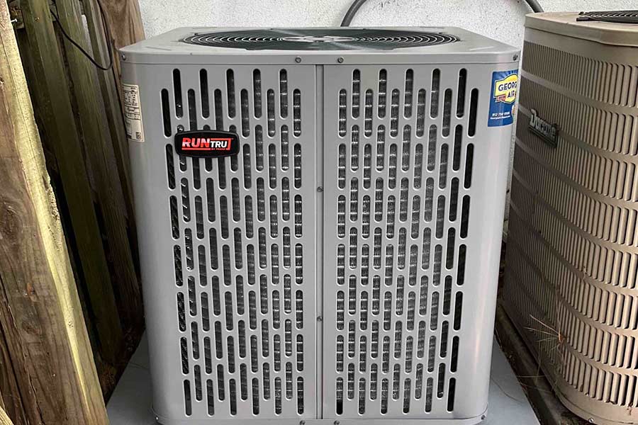 Outdoor air conditioning unit with Georgia Air branding near a wooden fence