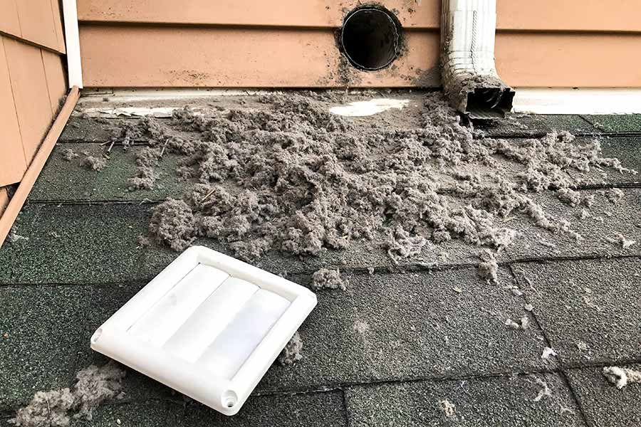 A clogged exterior dryer vent covered in lint, restricting airflow