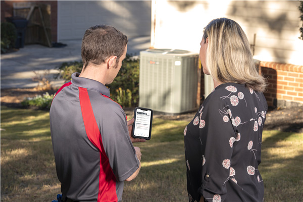 Professional technician consulting with a customer about HVAC maintenance using a tablet or mobile device