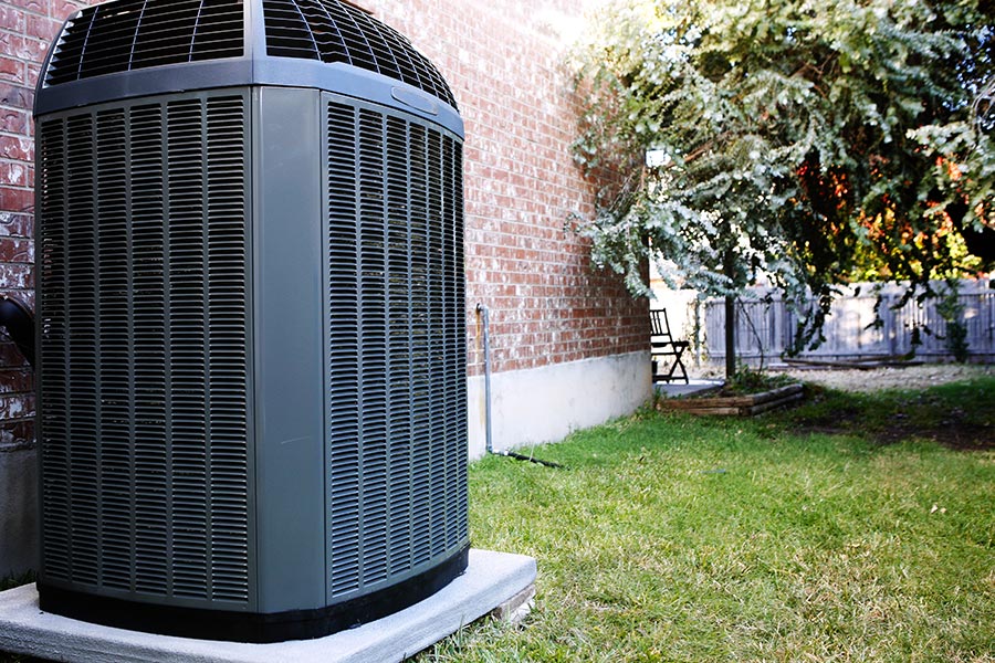 Large outdoor air conditioning unit next to a brick house